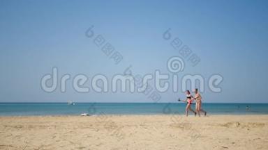 两个年轻的女朋友穿着泳装沿着海岸跑，不受相机的关注。 休闲和旅游的概念